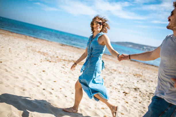 istock Heterosexual couple holding hands and having fun on the beach 1214323386