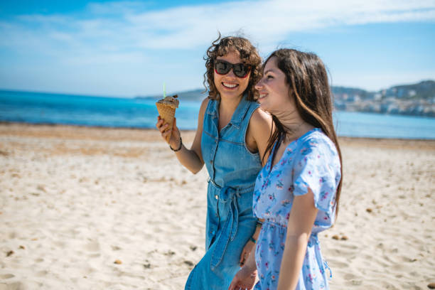 istock Two female friends sitting on the beach and talking 1214323396
