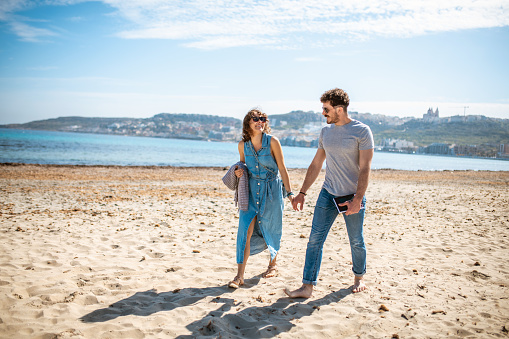 Heterosexual couple walking on the beach and holding hands