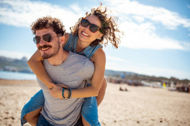 istock Boyfriend carrying his girlfriend piggyback on the beach 1214324593
