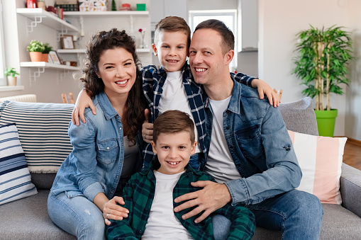 Portrait of a Young Happy Family Smiling at Home Together on the Sofa in the Living Room Enjoy Free Time. Weekend Activity Happy Family Lifestyle Concept