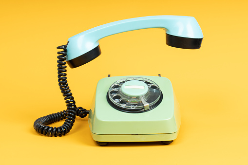 Old telephone on yellow background. Vintage phone with taken off receiver