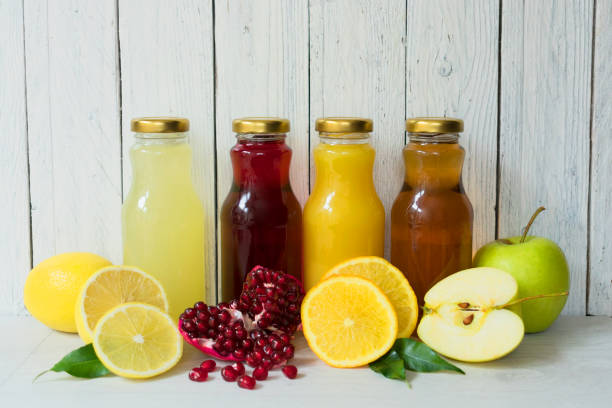 istock Four types of juice (pomegranate, apple, lemon, orange juice) in glass bottles on a white background. 1214326231
