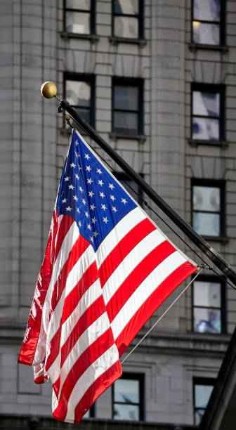 American flag with building facade in background, New York.