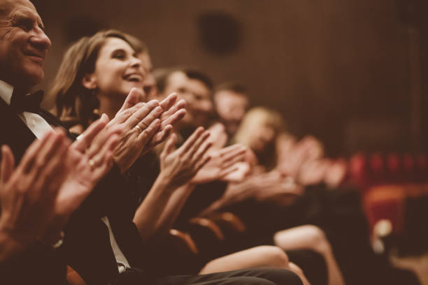 Excited audience clapping in the theater Side view of smiling spectators clapping hands in opera house. Men and women are watching theatrical performance. They are in elegant wear. classical concert photos stock pictures, royalty-free photos & images