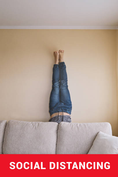 istock Man handstanding behind couch. People goes crazy in quarantine 1214326743