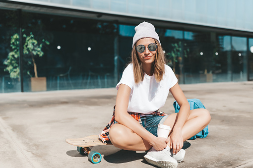Attractive woman in sunglasses relaxing sitting on the longboard