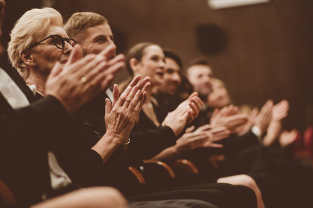 Excited spectators clapping in the theater, focus on hands Side view of smiling audience clapping hands in opera house. Men and women are watching theatrical performance. They are in elegant wear. opera stock pictures, royalty-free photos & images