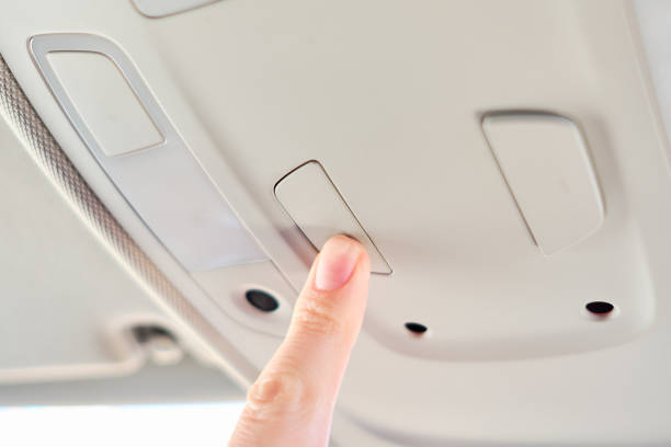 istock A man in a modern car. Hand presses the button with the light on the panel. 1214330409