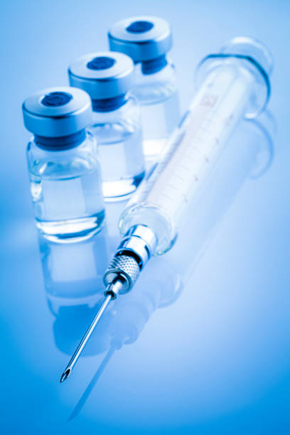 istock Coronavirus vaccine: syringe and vials on blue background 1214330597