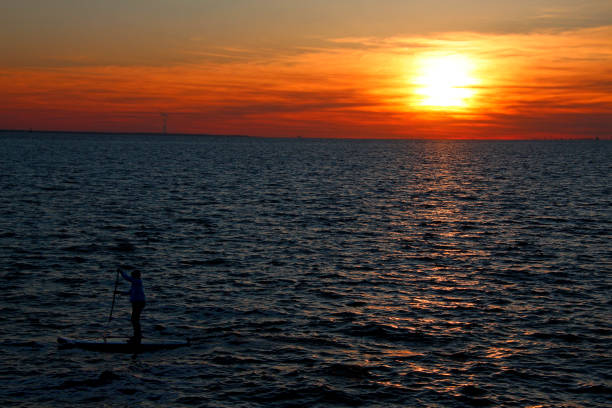 istock man floating on a board with a paddle on a sunset background 1214331433