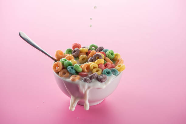 istock bright multicolored breakfast cereal in bowl with splashing milk and spoon on pink background 1214331724