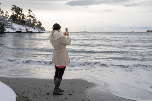 frau steht auf verschneiten strand nimmt foto von entfernten szene - 16642 stock-fotos und bilder