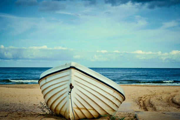 barca solitaria sdraiata sulla spiaggia di sabbia sulla costa dell'isola usedom, germania. - rowboat nautical vessel usedom sand foto e immagini stock