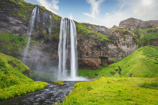 Famous Seljalandsfoss Waterfall close to Route 1 under blue summer sky. The Seljalandsfoss waterfall is around 60m high and part of the Seljalands River which has its origin in the volcano glacier Eyjafjallajökull. Route 1, Southern Iceland, Iceland, Nordic Countries, Europe
