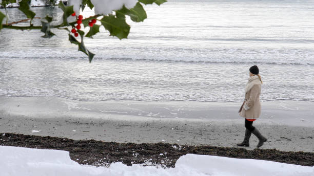 woman walks along beach at sunrise - winter women zen like photography imagens e fotografias de stock