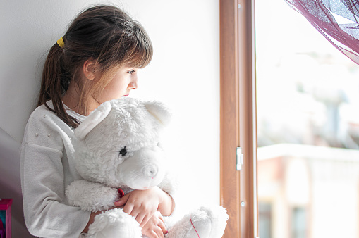 Little cute girl boring at home with her teddy bear