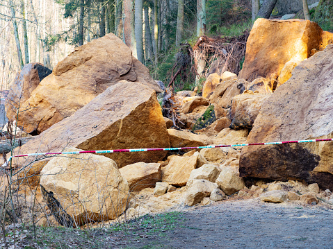 Zone of collapsed rock from the hill. Police closed forest path with white red tape. Danger place, do not entry.