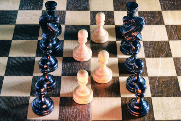 istock Old chess on a wooden Board - a white pawns surrounded by black 1214337043