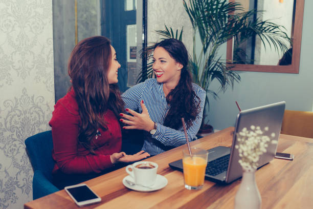 istock Two female friends using laptop and drinking coffee together 1214337896