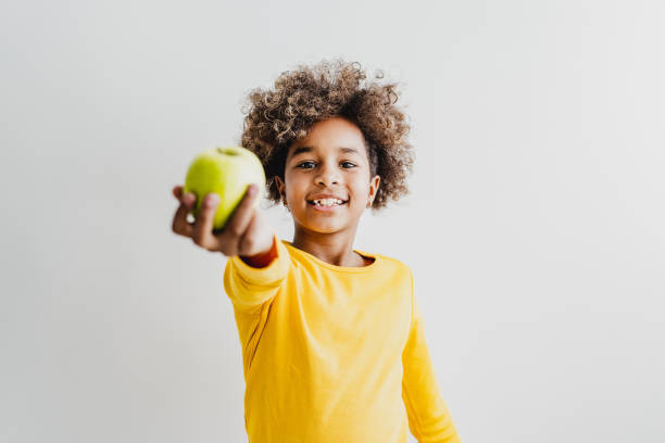 健康の象徴として緑のリンゴを持つ若い女の子 - child eating apple fruit ストックフォトと画像