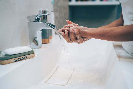 Cropped shot of an unrecognizable woman washing her hands in the bathroom at home