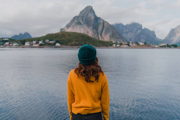mujer mirando el pueblo de reine en las islas lofoten - fishing village nordic countries fjord fotografías e imágenes de stock