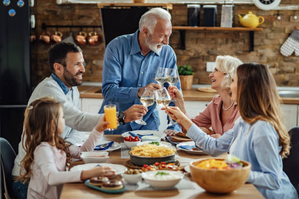 istock Happy multi-generation family toasting while having lunch at home. 1214340760