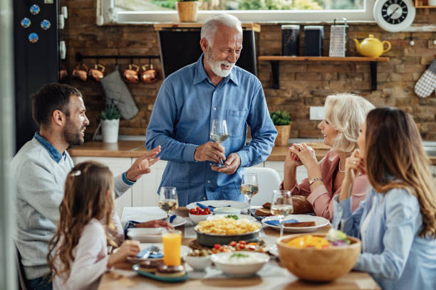 istock Happy senior man talking to his family while proposing a toast at dining table. 1214340960