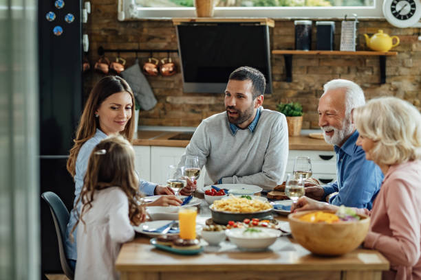 istock Happy extended family talking while having lunch at dining table. 1214341017