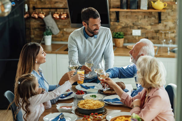 istock Happy multi-generation family toasting while having lunch together at home. 1214341102