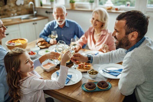 happy little girl toasting with her family during lunch at dining table. - drinking little girls women wine imagens e fotografias de stock