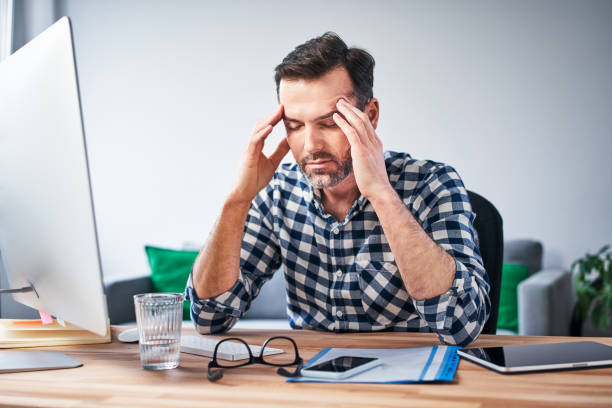 istock Overworked man suffering migraine, working on computer from home office 1214342306