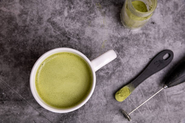 Cup or fresh, organic Matcha Latte with matcha powder next to it.