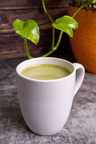Cup or fresh, organic Matcha Latte with matcha powder next to it.