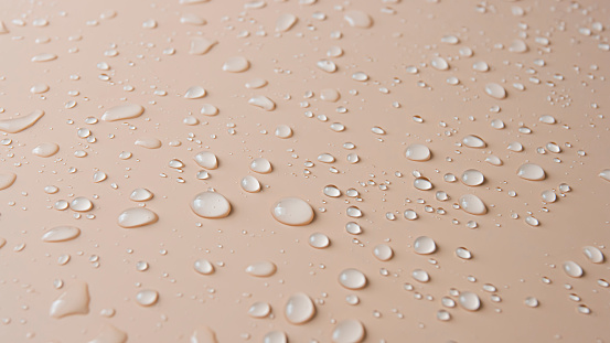 Lots of different rain water drops on a beige background, top view