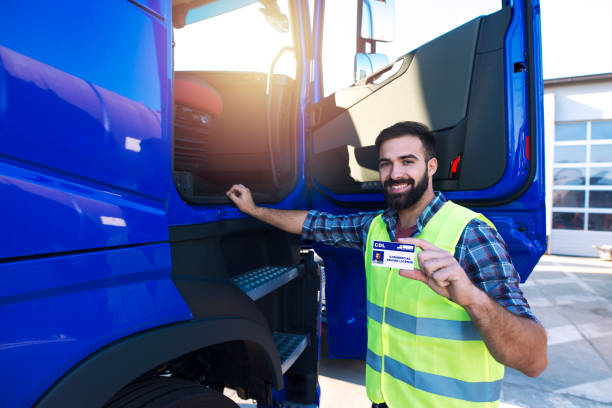 Truck driver candidate showing CDL driving license. Successfully passed training driving exam. Truck driving school and candidate training. drivers license stock pictures, royalty-free photos & images