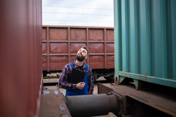 istock Railway worker checking freight train cars before departure. Worker inspecting cargo shipping containers. 1214345518