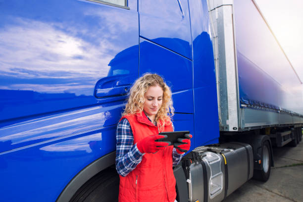 istock Professional truck driver setting up navigation for destination. Checking his route on tablet computer and standing by long vehicle. Transportation service. 1214346119