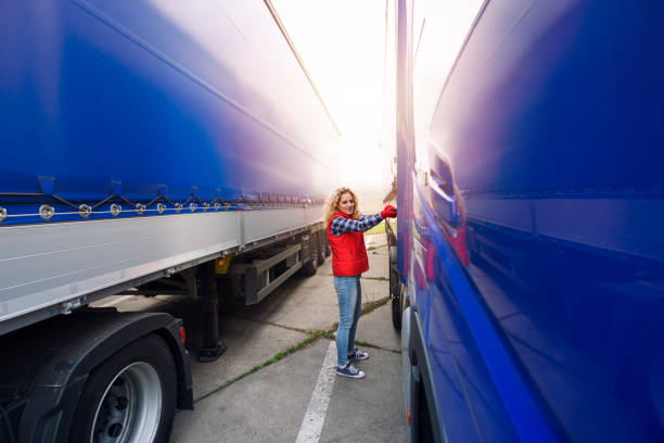 Female trucker removing canvas tarpaulin to prepare truck for unloading. Female driver taking of truck trailer tarpaulin plastic cover. unloading photos stock pictures, royalty-free photos & images