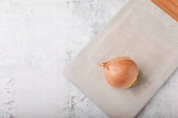 ganze süße zwiebel auf zement schneidebrett auf zement-arbeitsplatte - sweet onion stock-fotos und bilder