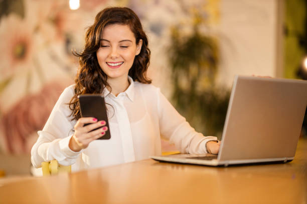 istock Woman using smart phone and laptop at cafe 1214351335
