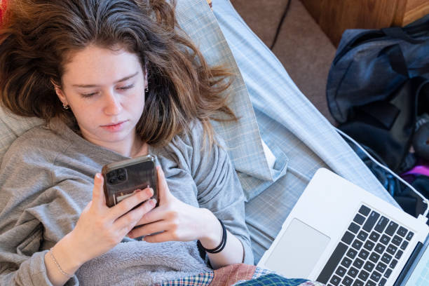 Self-isolation is your safety. Teenager girl lying in a bed and surfing social media during the quarantine because of Coronavirus outbreak. Quarantine at home during pandemic outbreak. epidemiology student stock pictures, royalty-free photos & images