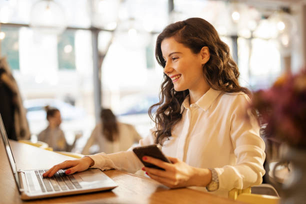 istock Woman using smart phone and laptop at cafe 1214351739