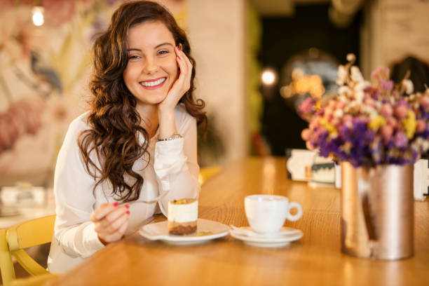 mujer comiendo pastel y bebiendo café en la cafetería - espresso coffee cream coffee shop fotografías e imágenes de stock