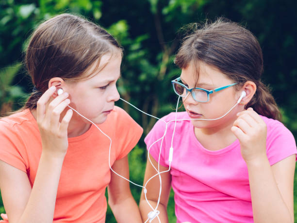 dziewczyny dzielące słuchawki do słuchania muzyki - chewing gum audio zdjęcia i obrazy z banku zdjęć