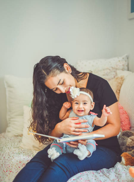 madre lee libro para dulce bebé de 6 meses - puertorriqueño fotografías e imágenes de stock