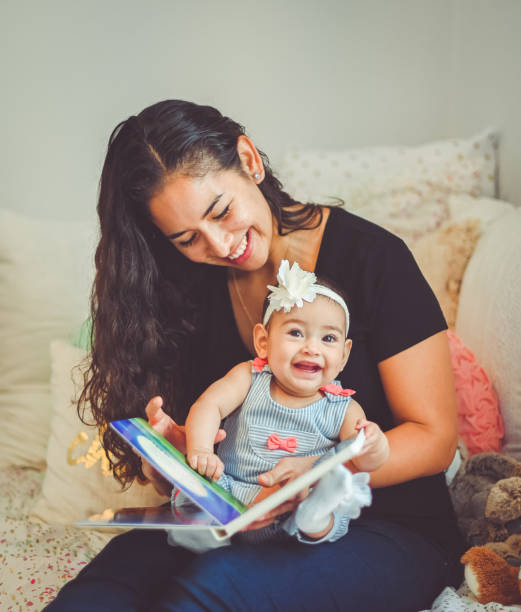 mother reads book to sweet 6 month old baby - puerto rican ethnicity women smiling cheerful imagens e fotografias de stock