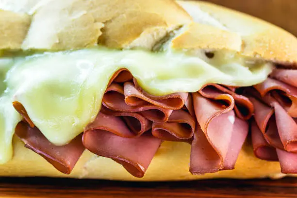 Photo of bread with mortadella and melted cheese. Rustic wooden background, São Paulo meal, famous bread and mortadella from São Paulo market.