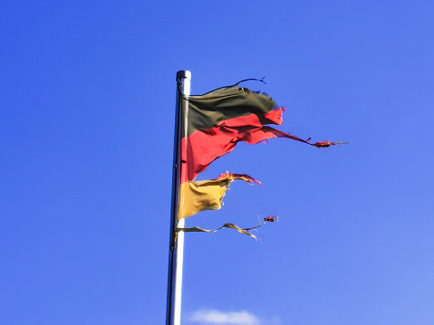 destroyed German national flag (black, red, gold) waving in the wind